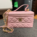 Ce sac vanity case Chanel rose est confectionné en cuir matelassé et agrémenté d'une chaîne dorée.