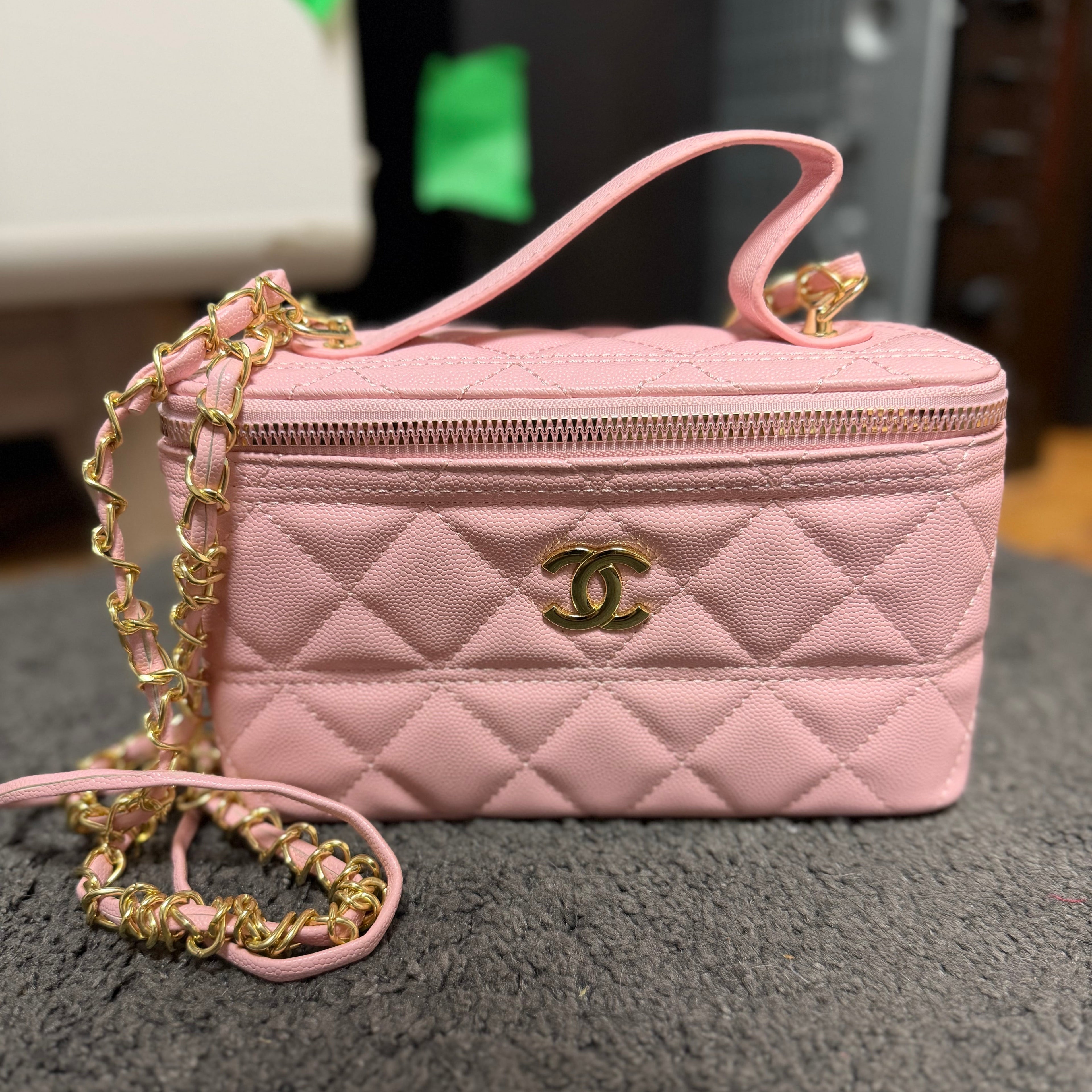 Ce sac vanity case Chanel rose est confectionné en cuir matelassé et agrémenté d'une chaîne dorée.