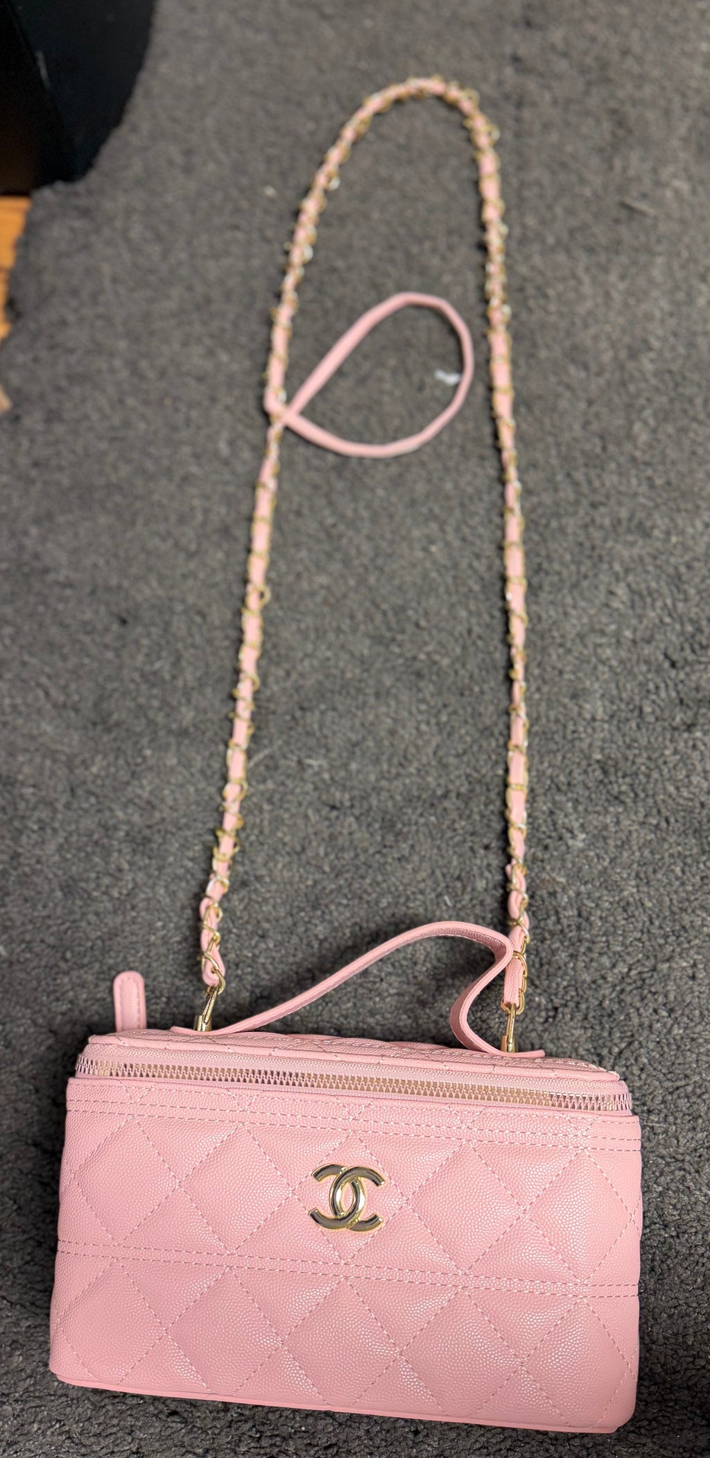 Ce sac vanity case Chanel rose est confectionné en cuir matelassé et agrémenté d'une chaîne dorée.