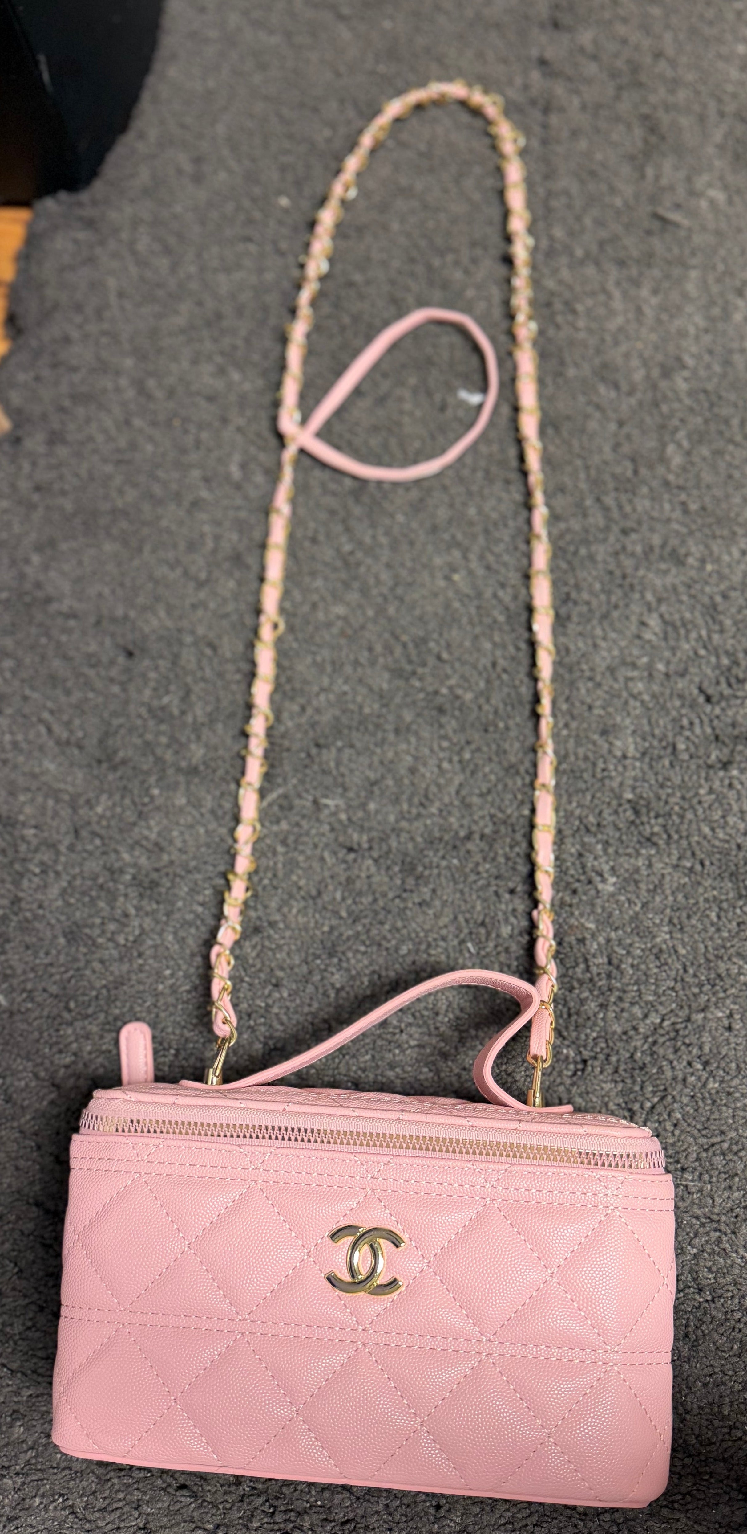 Ce sac vanity case Chanel rose est confectionné en cuir matelassé et agrémenté d'une chaîne dorée.