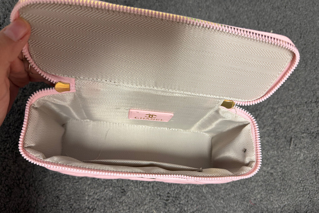 Ce sac vanity case Chanel rose est confectionné en cuir matelassé et agrémenté d'une chaîne dorée.